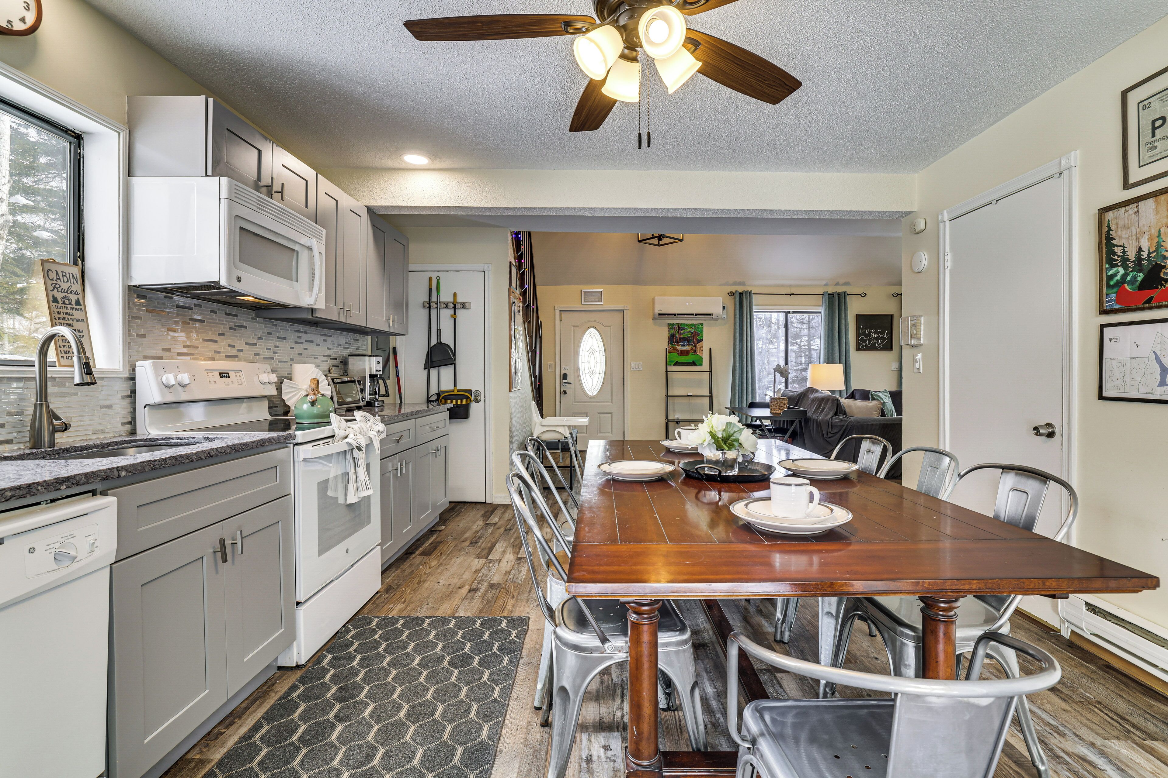 A modern kitchen with white cabinets, a microwave, and a wooden dining table with chairs.