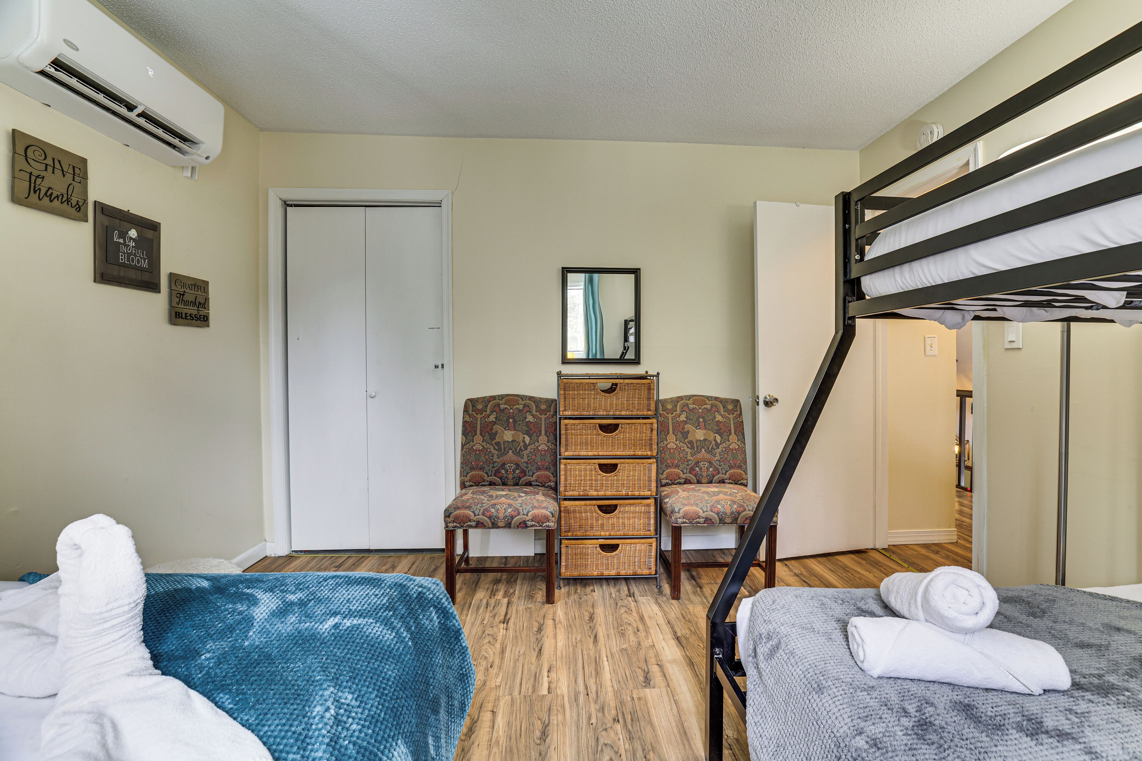 A bedroom with a bunk bed, two chairs, a dresser, and a mirror.