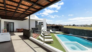 Un'area esterna coperta con piscina, sedie a sdraio e angolo ristoro.