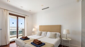 Una camera d'albergo con due letti, un balcone e vista sulla città.
