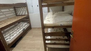 A dormitory room with bunk beds, a tiled floor, and a door. - House with pool in Itanhaém | Ideal for families and groups (Itanhaém)