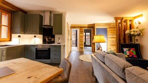 Een moderne keuken met grijze kastjes, een houten eettafel en een bank in de woonkamer.