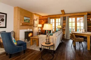 A cozy log cabin interior with a sofa, armchair, and dining table. - Hirondelle Chalet (Sainte-Foy-Tarentaise)