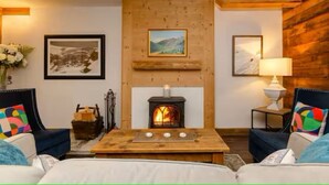 Een gezellige kamer met een open haard, twee banken, een salontafel en beelde achter de wanden.