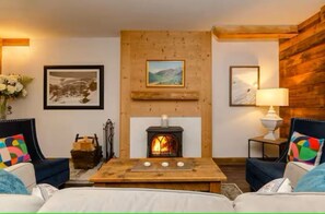 A cozy room with a fireplace, two sofas, a coffee table, and framed pictures on the walls. - Hirondelle Chalet (Sainte-Foy-Tarentaise)