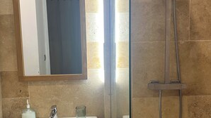 Un bagno con lavandino bianco, box doccia in vetro e specchio con cornice in legno.