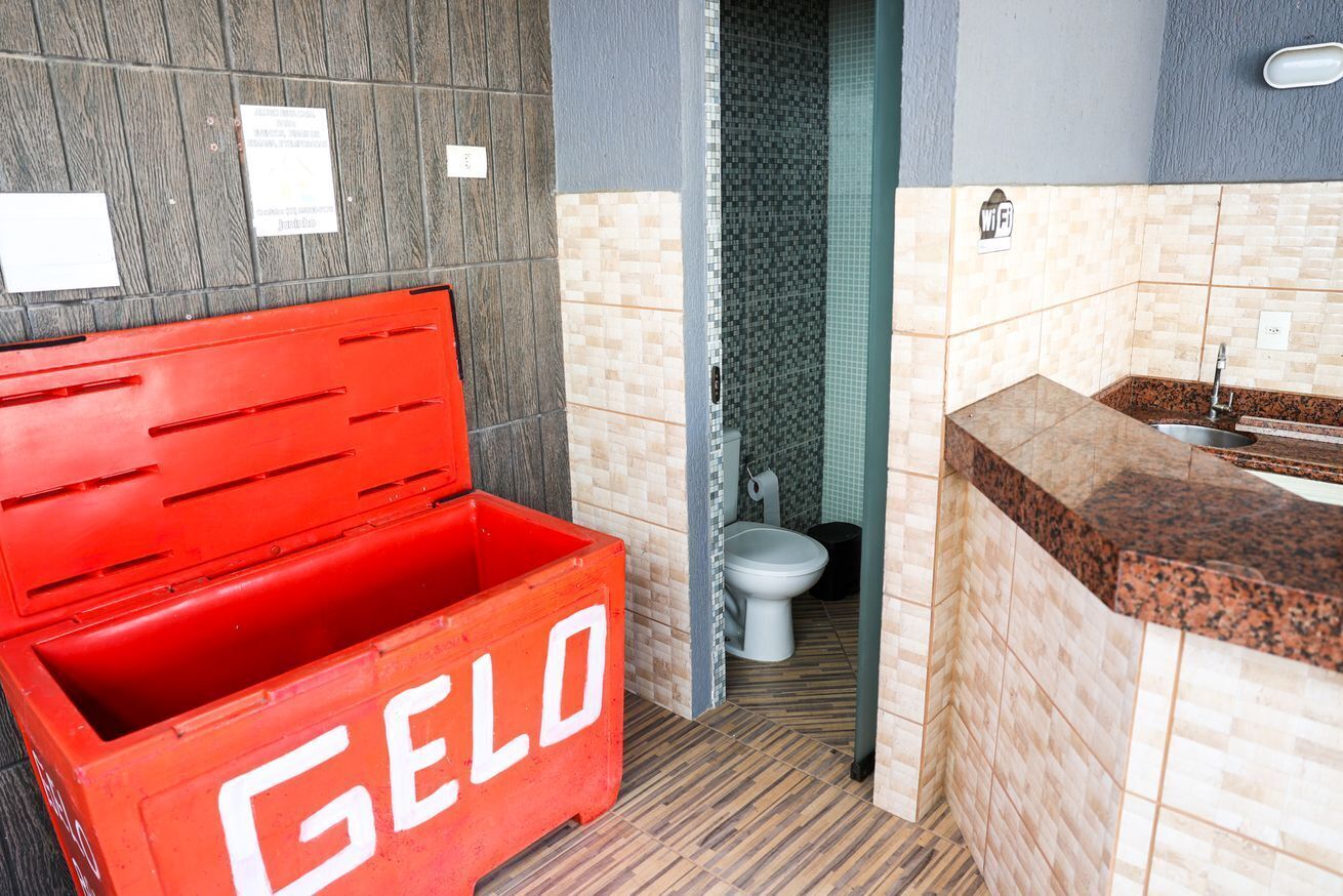A bathroom with a red storage box labeled 'GELO', a toilet, and a sink with a tiled backsplash.
