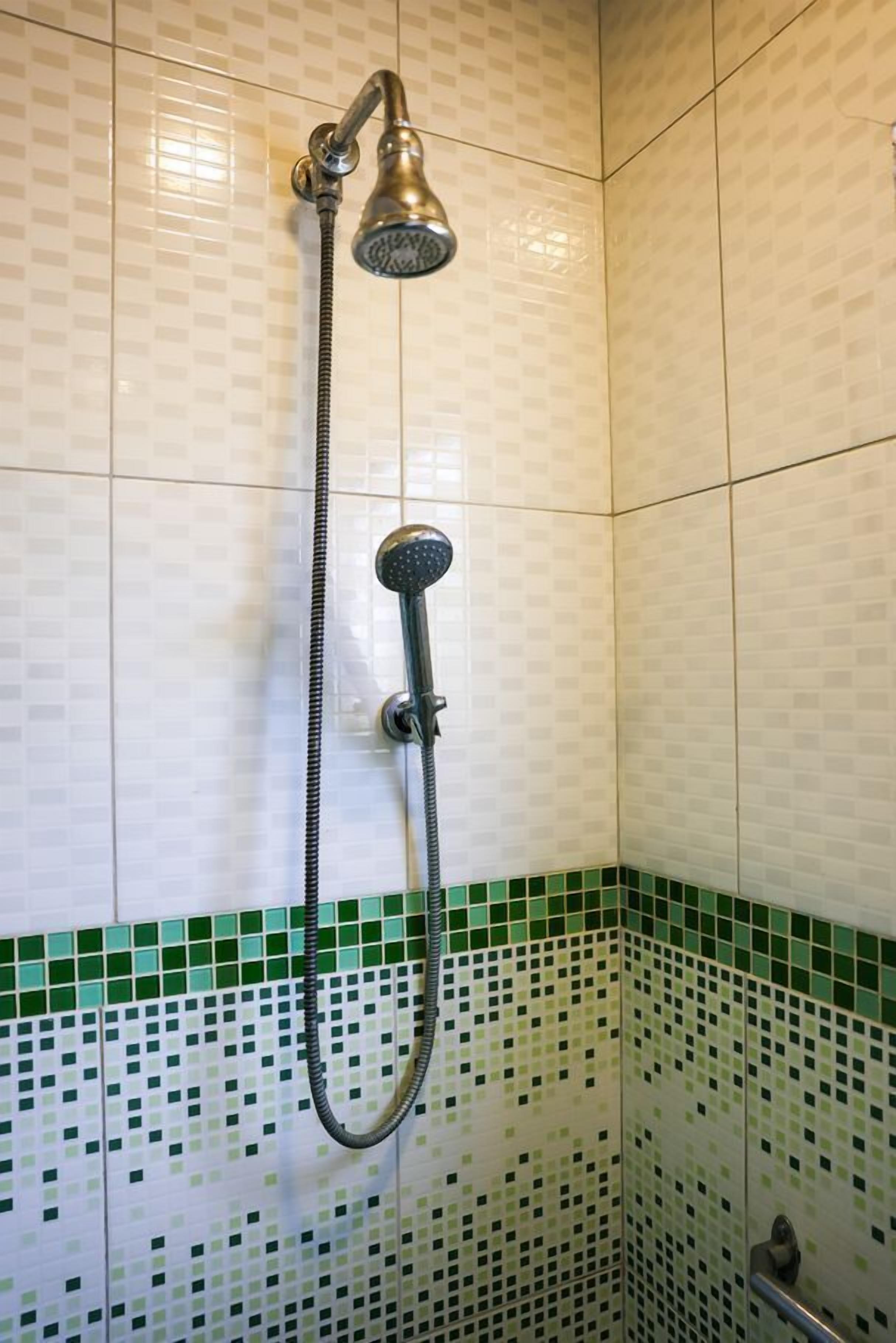 Une douche équipée d’un pommeau de douche à main et d’un pommeau de douche fixe fixé au mur.
