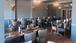 A restaurant with booths and tables, wooden flooring, and modern lighting fixtures.