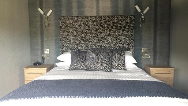 A bedroom with a large bed, two bedside tables, and a patterned headboard.