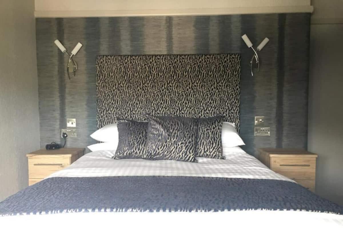 A bedroom with a large bed, two bedside tables, and a patterned headboard.