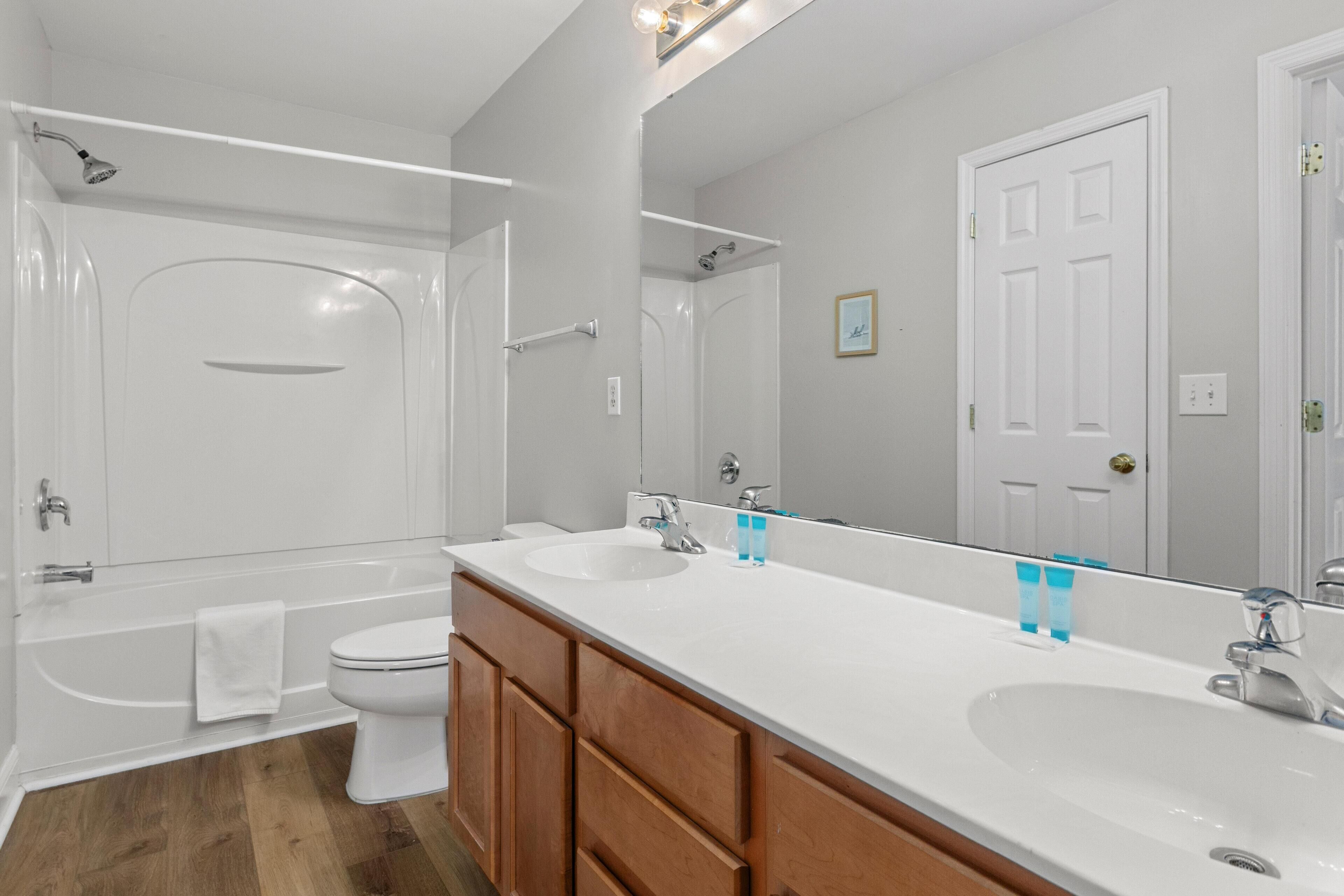 A modern bathroom with a bathtub, two sinks, and wooden cabinets.