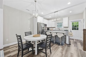 Una cocina moderna con armarios blancos, electrodomésticos de acero inoxidable y una mesa redonda con sillas.