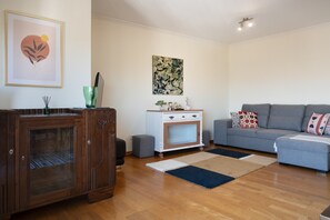 Un soggiorno con un mobile in legno, un divano grigio, un tavolino bianco e un grande quadro astratto appeso alla parete.