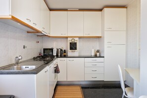 Una cucina moderna con mobili bianchi, un piano di lavoro in granito, un lavello, un fornello e un menu scritto su una lavagna.