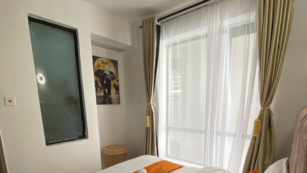 Una camera d'albergo con un letto, una finestra con tende, un quadro appeso al muro e un lampadario.