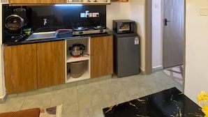 Una cucina compatta con mobili in legno, piano cottura integrato, forno a microonde e lavello.