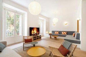 Ein modernes Wohnzimmer mit Kamin, bequemen Sitzmöglichkeiten und großen Fenstern.