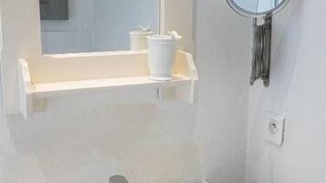 A bathroom with a white sink, a mirror, and a shelf with toiletries.