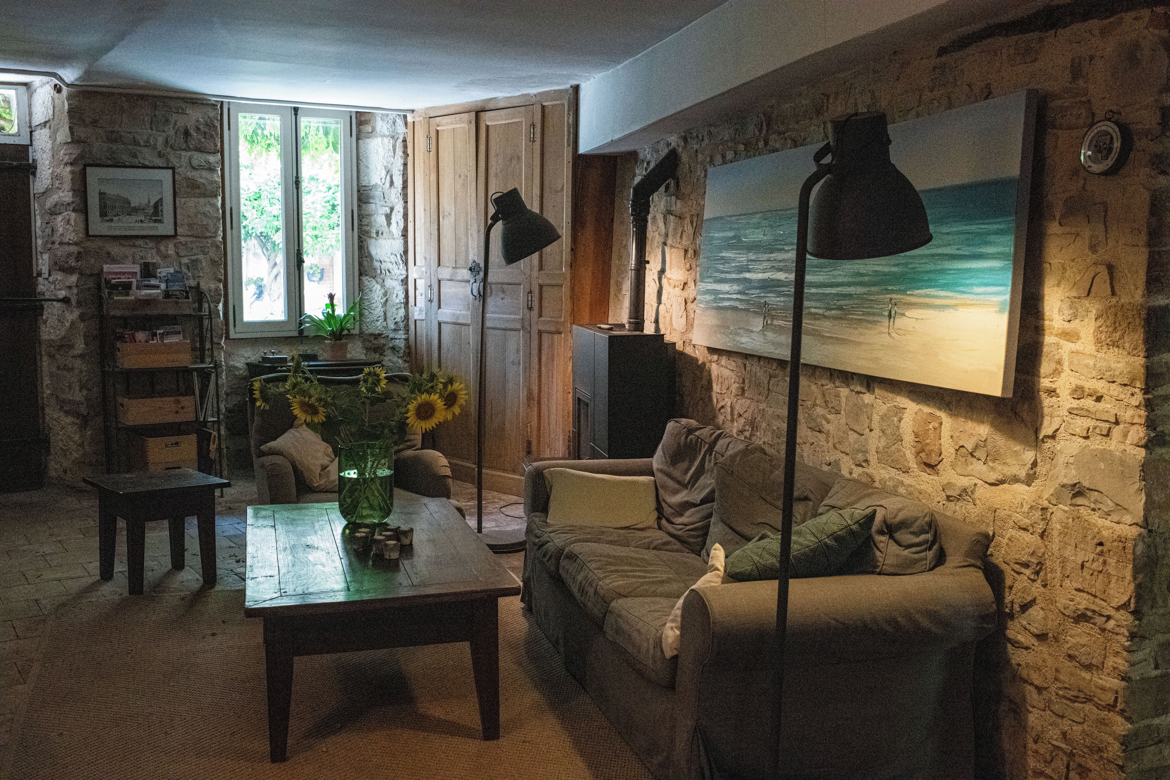 Una sala de estar acogedora con una pared de piedra, un cuadro de una playa, un sofá, una mesa de centro y una estantería.