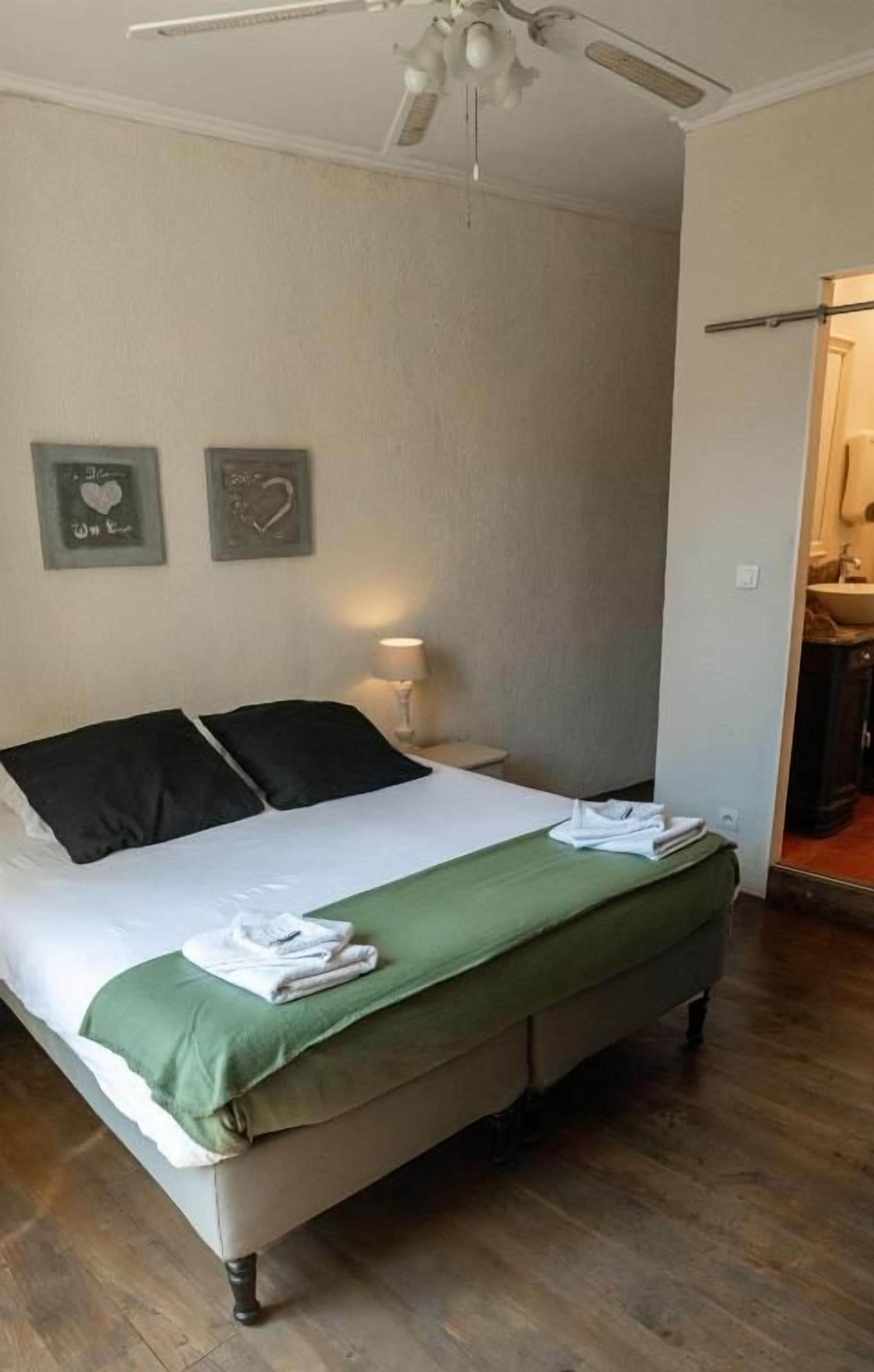 Une chambre à coucher avec un lit, une table de chevet, une lampe et un ventilateur de plafond.