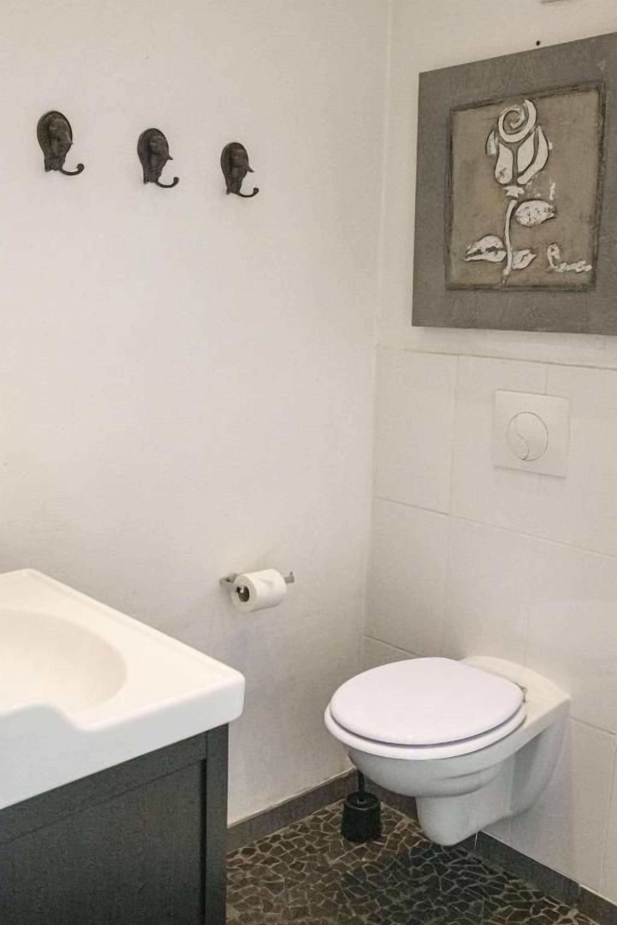 A bathroom with a toilet, sink, and a wall-mounted rose decoration.