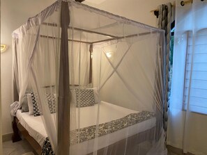 A bed with a canopy, pillows, and a bedside table. - Charming 1-bedroom villa with AC in beautiful Mtwapa (Mtwapa)