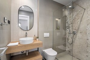 Ein modernes Badezimmer mit rundem Spiegel, Waschbecken und einer Duschkabine.