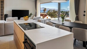 Una moderna camera d'hotel con angolo cottura, un tavolo da pranzo e un'ampia finestra con vista sulle montagne.