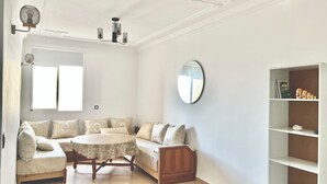 Una sala de estar con una mesa redonda, un sofá, un mueble de madera y una estantería.