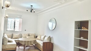 Una sala de estar con una mesa redonda, sofá y una estantería.