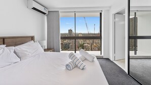 Une chambre d’hôtel moderne avec un grand lit, une vue sur la ville et un ventilateur de plafond.