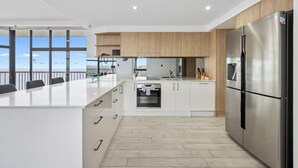 Une cuisine moderne dotée d’un grand îlot central, d’appareils électroménagers en acier inoxydable et de meubles en bois.