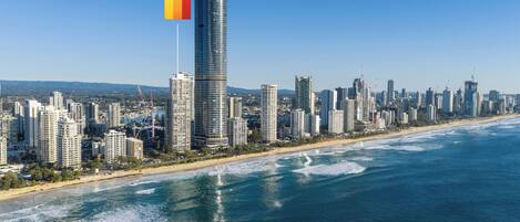 Un paisaje urbano costero con un rascacielos destacado que exhibe una bandera.