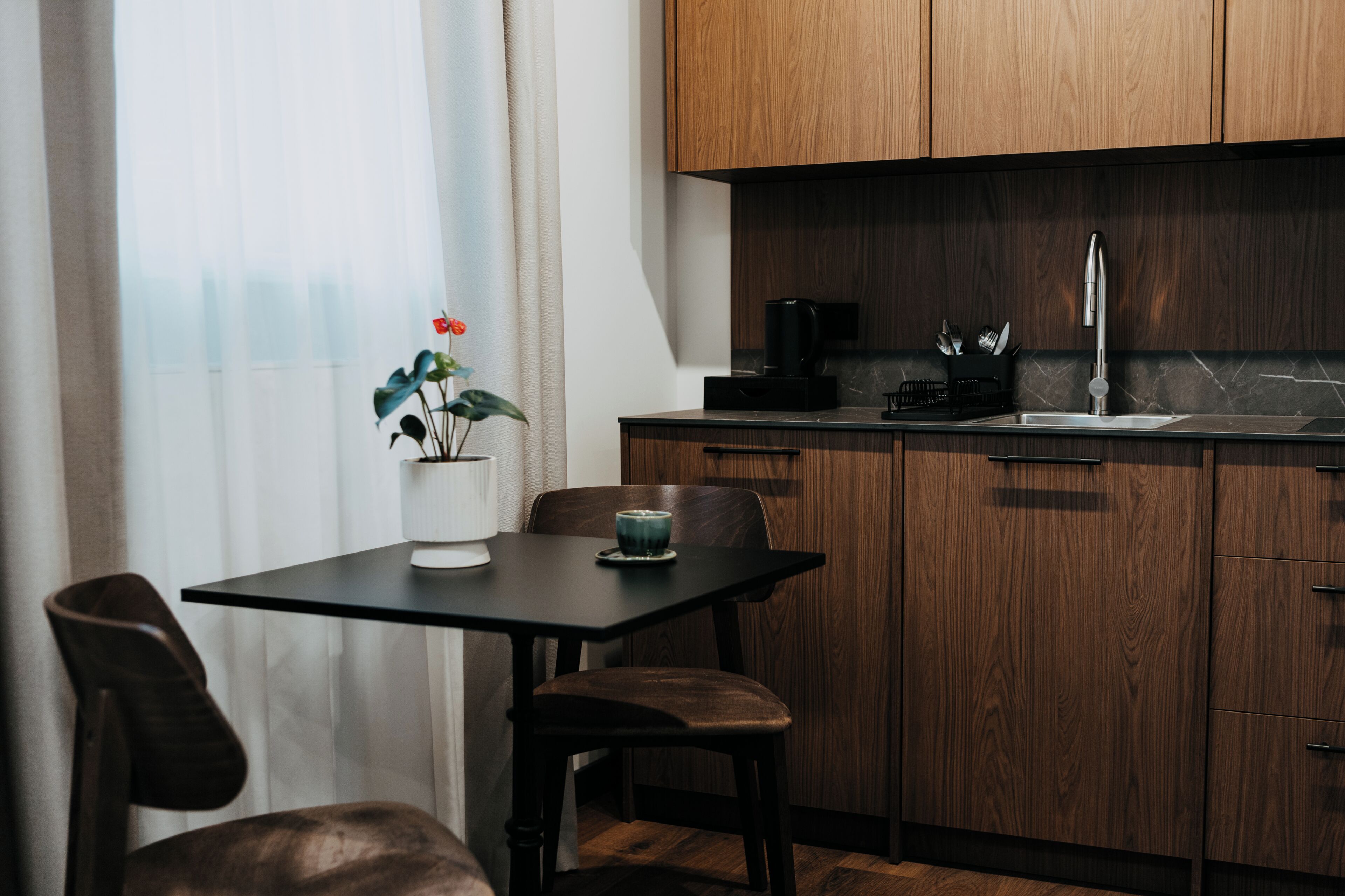 Una cocina moderna con armarios de madera, encimera negra y una cafetera.