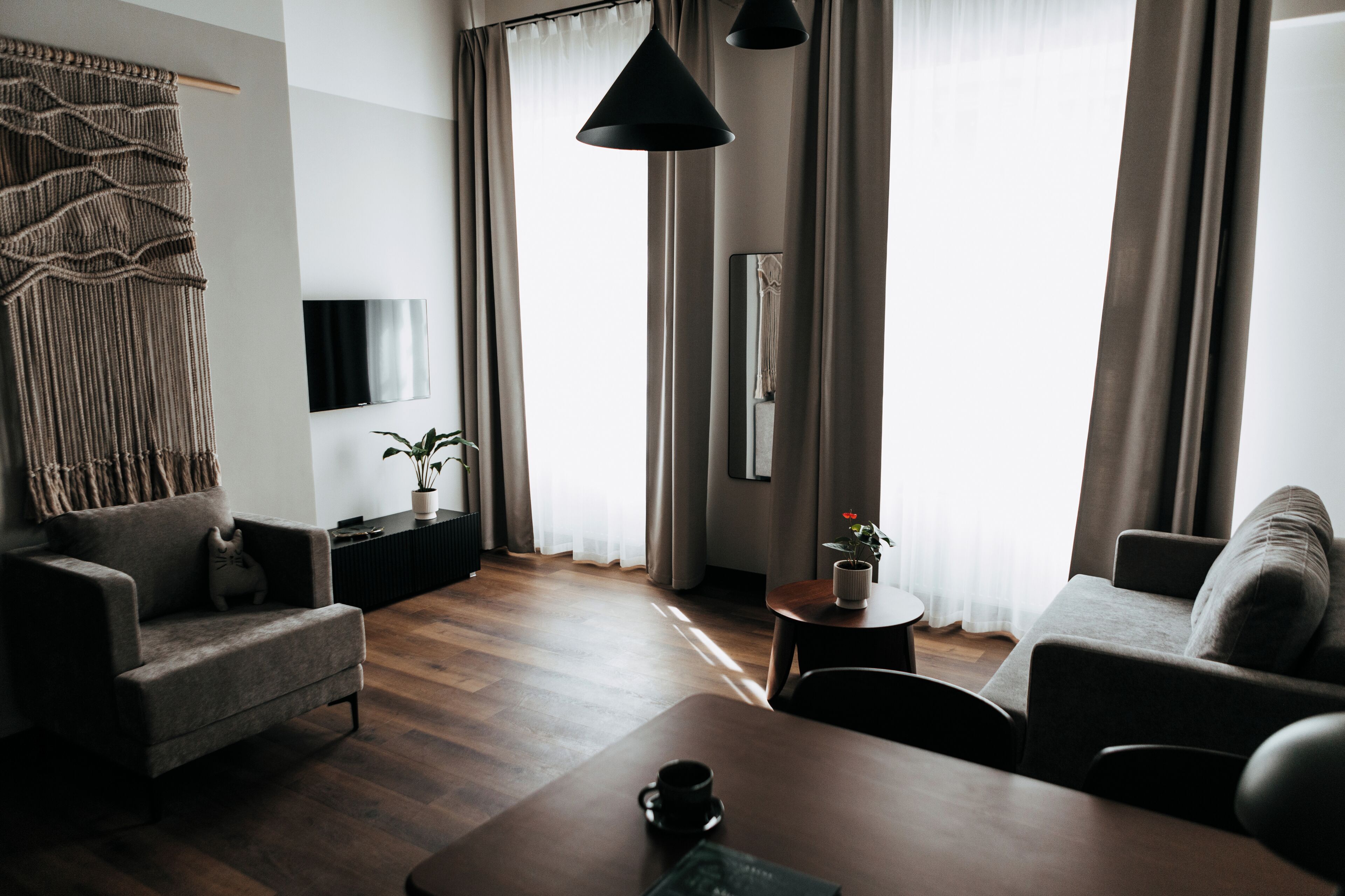 A modern living room with a sofa, armchair, coffee table, and a TV mounted on the wall.