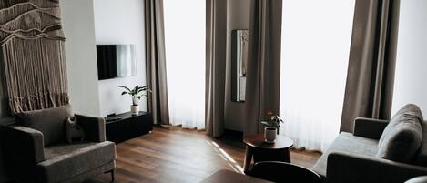A modern living room with a sofa, armchair, coffee table, and a TV mounted on the wall.