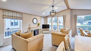 Ein gemütliches Wohnzimmer mit beigen Sofas, einem Fernseher und einem Kamin.