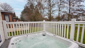 Ein Whirlpool auf einer Holzterrasse mit einem weißen Zaun.