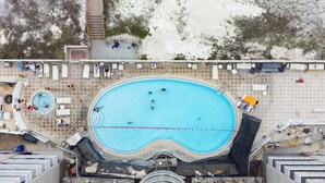 Piscina no terraço, rodeada por espreguiçadeiras e um deque coberto.