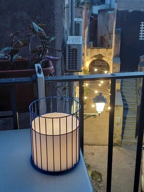 Ein Balkon mit Metallgeländer, einem Blumentopf und einer weißen Lampe.