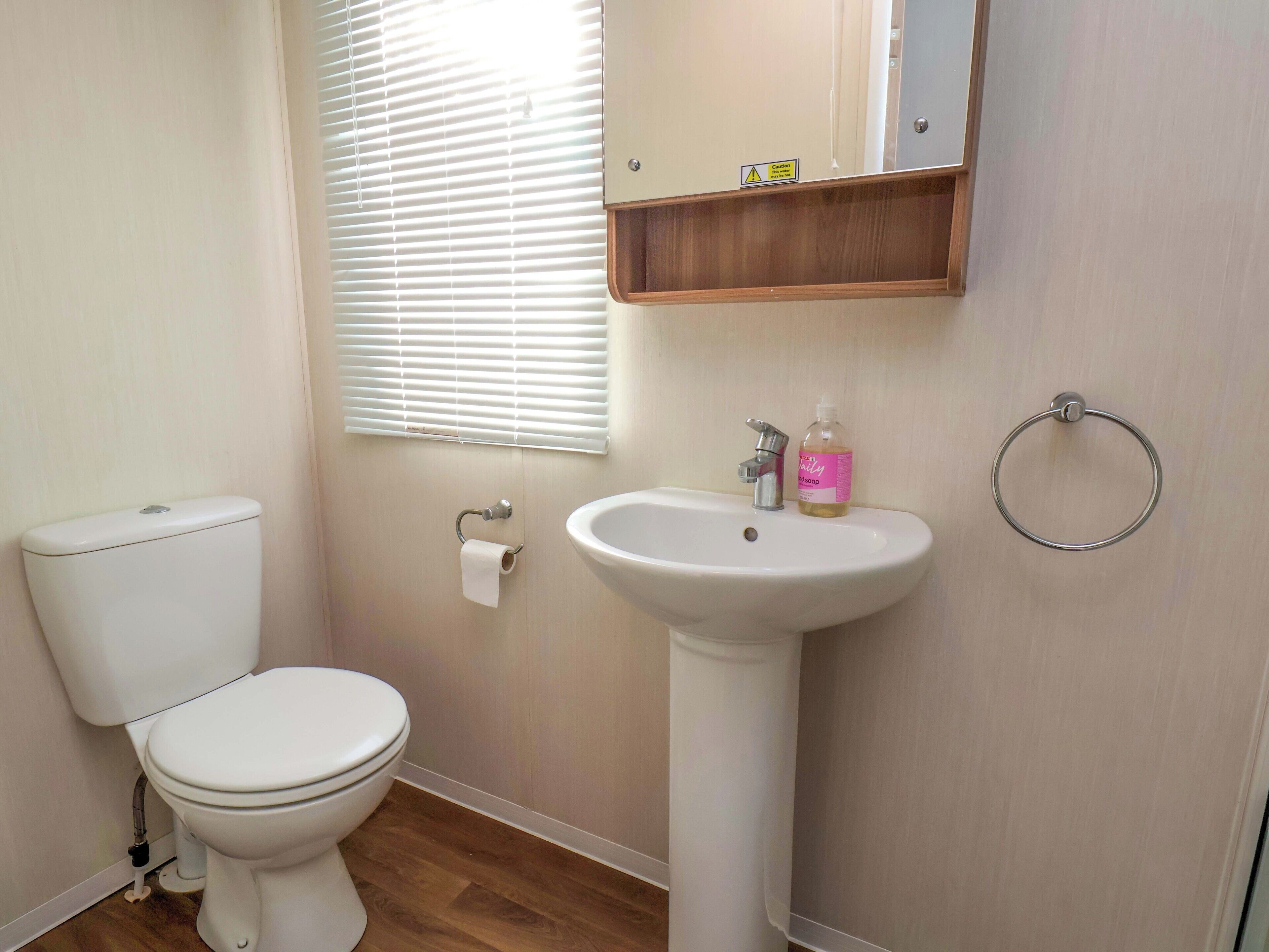 A bathroom with a toilet, sink, and window with blinds.