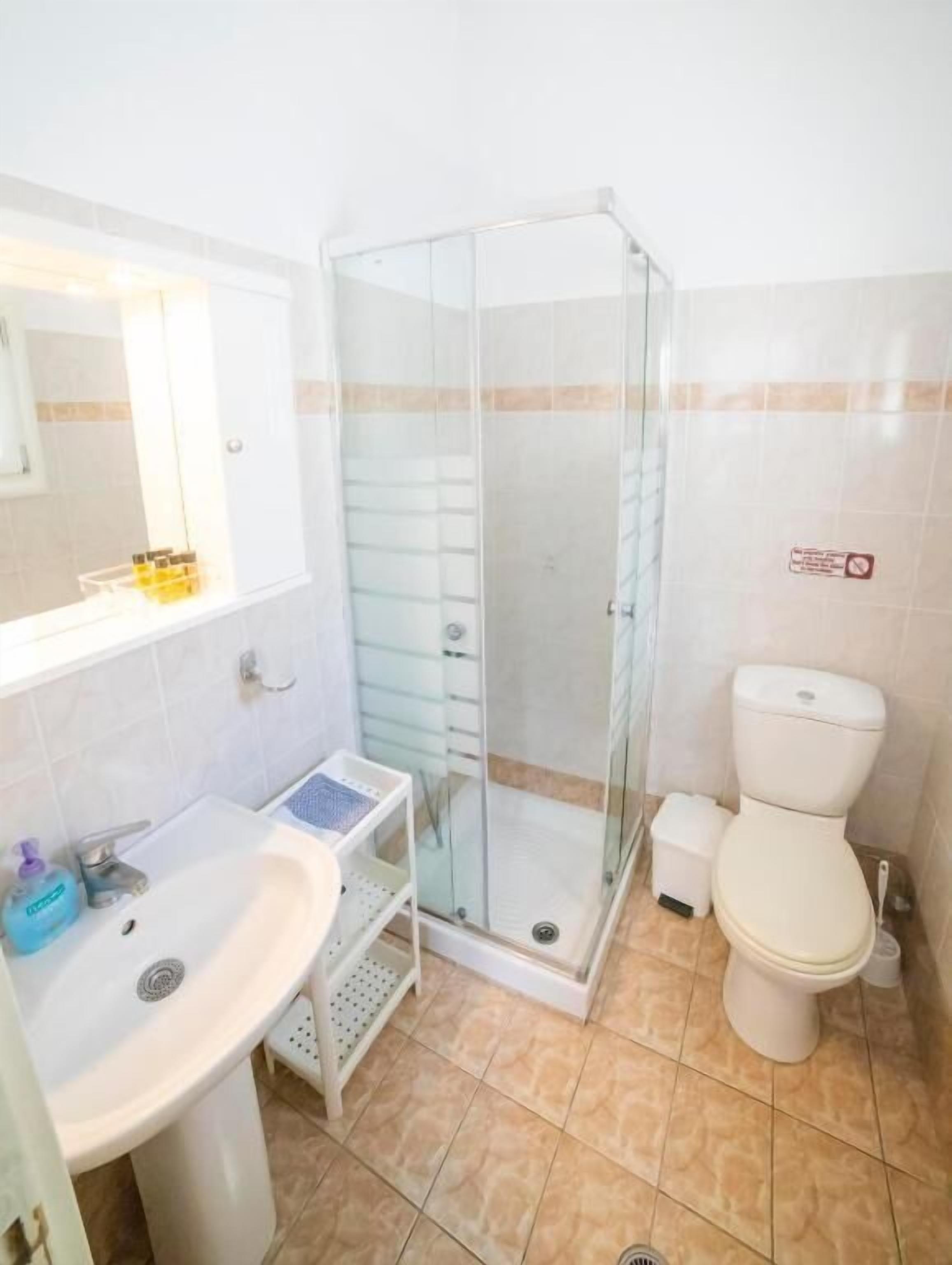 A bathroom with a glass-enclosed shower, a sink with a mirror, and a toilet.