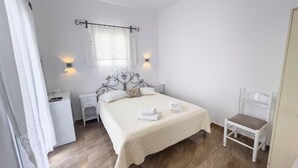Une chambre à coucher avec un lit, des tables de chevet, une chaise et une fenêtre avec des rideaux.
