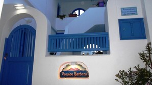 Un bâtiment avec une enseigne indiquant la réception, une porte bleue et une autre enseigne portant le nom « Pension Barbara ».