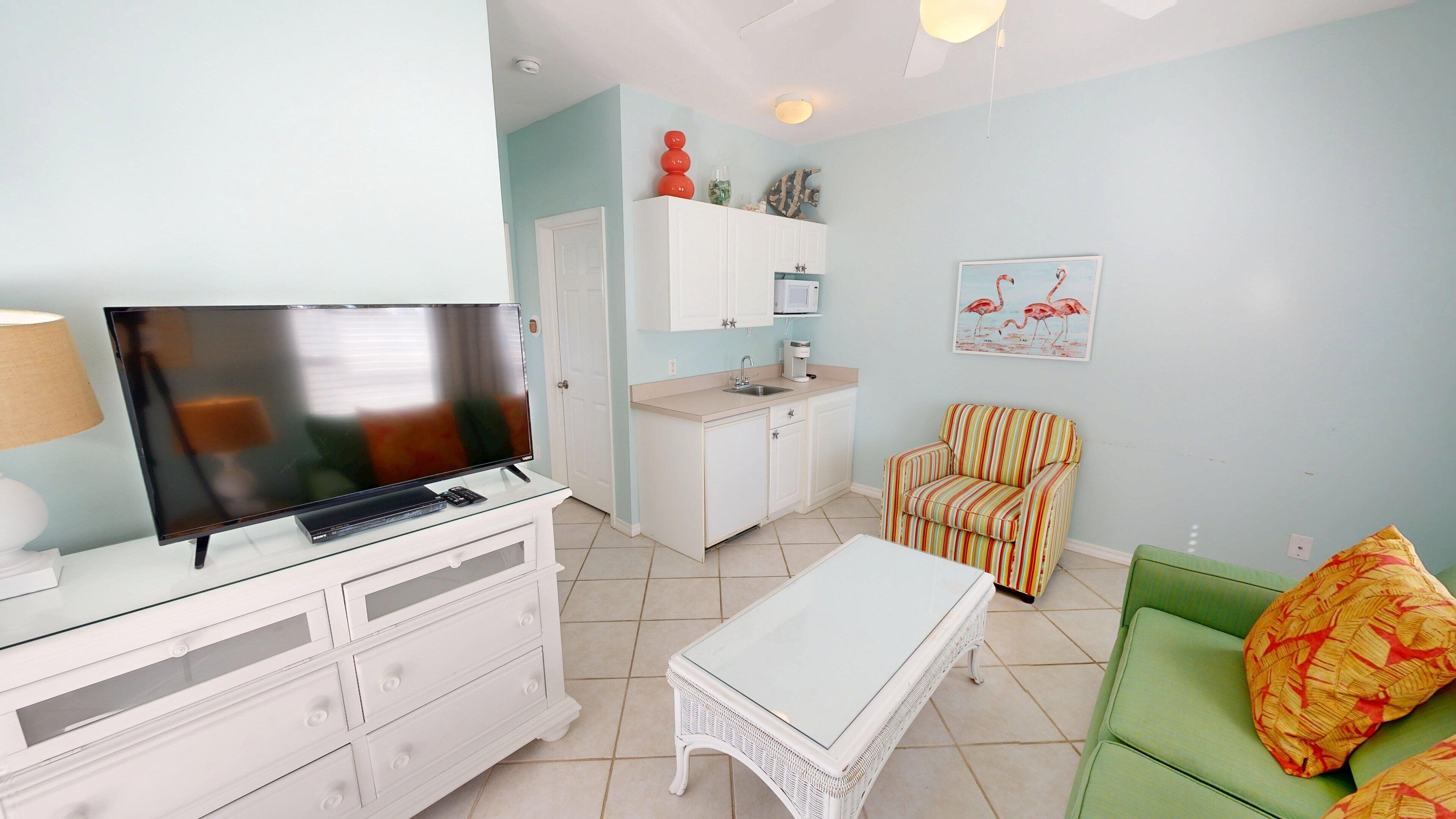 Un espacio habitable compacto con televisión, kitchenette y zona de estar.