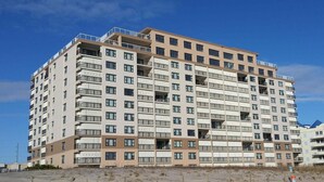 A multi-story residential building with balconies, located near a sandy area. - Sandpiper Dunes 605 2 Bedroom Condo (Ocean City)