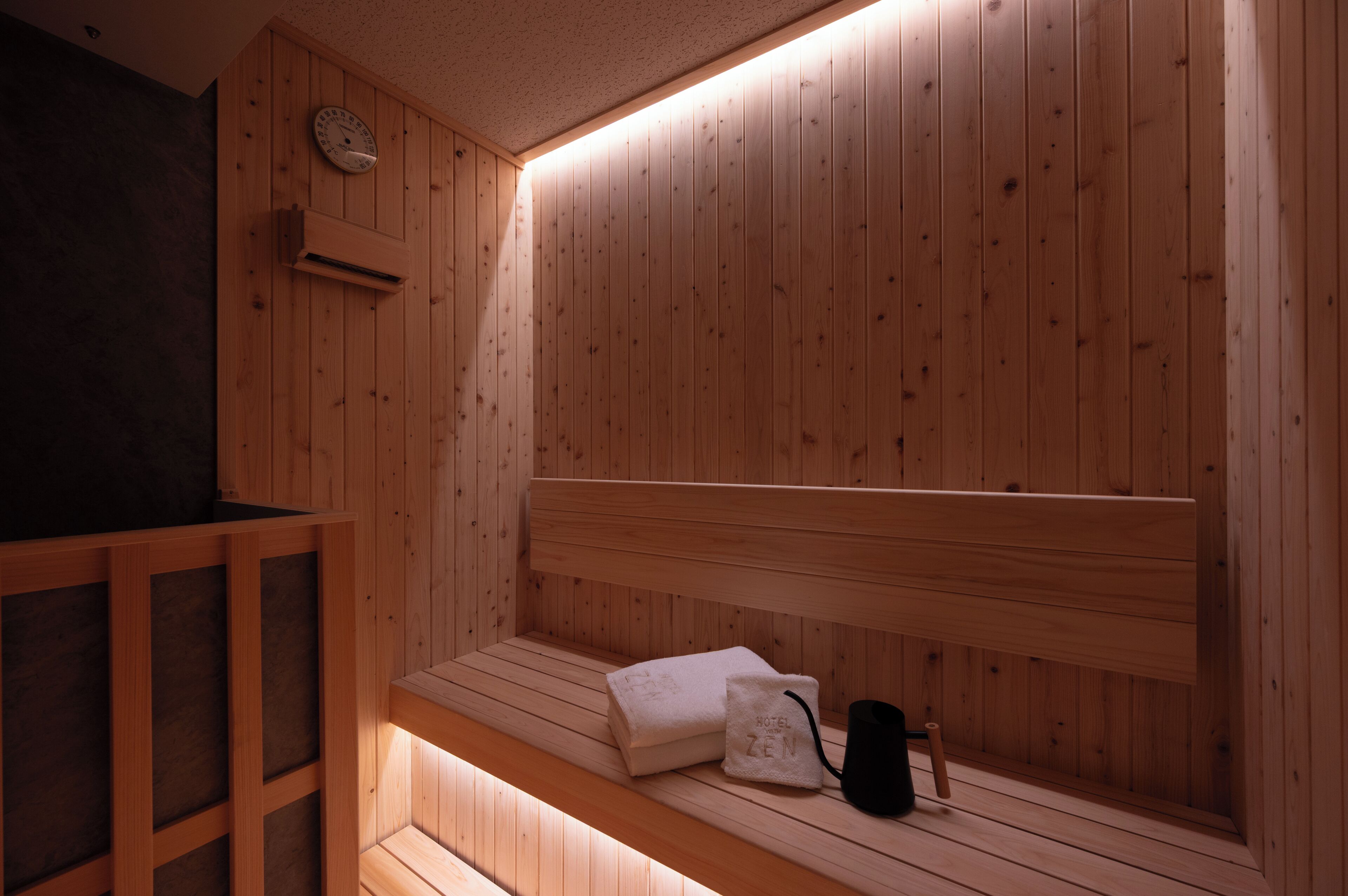 Un sauna en bois avec un banc, une serviette et un sac noir.