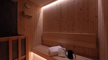 Una sauna de madera con un banco, una toalla y un bolso negro.