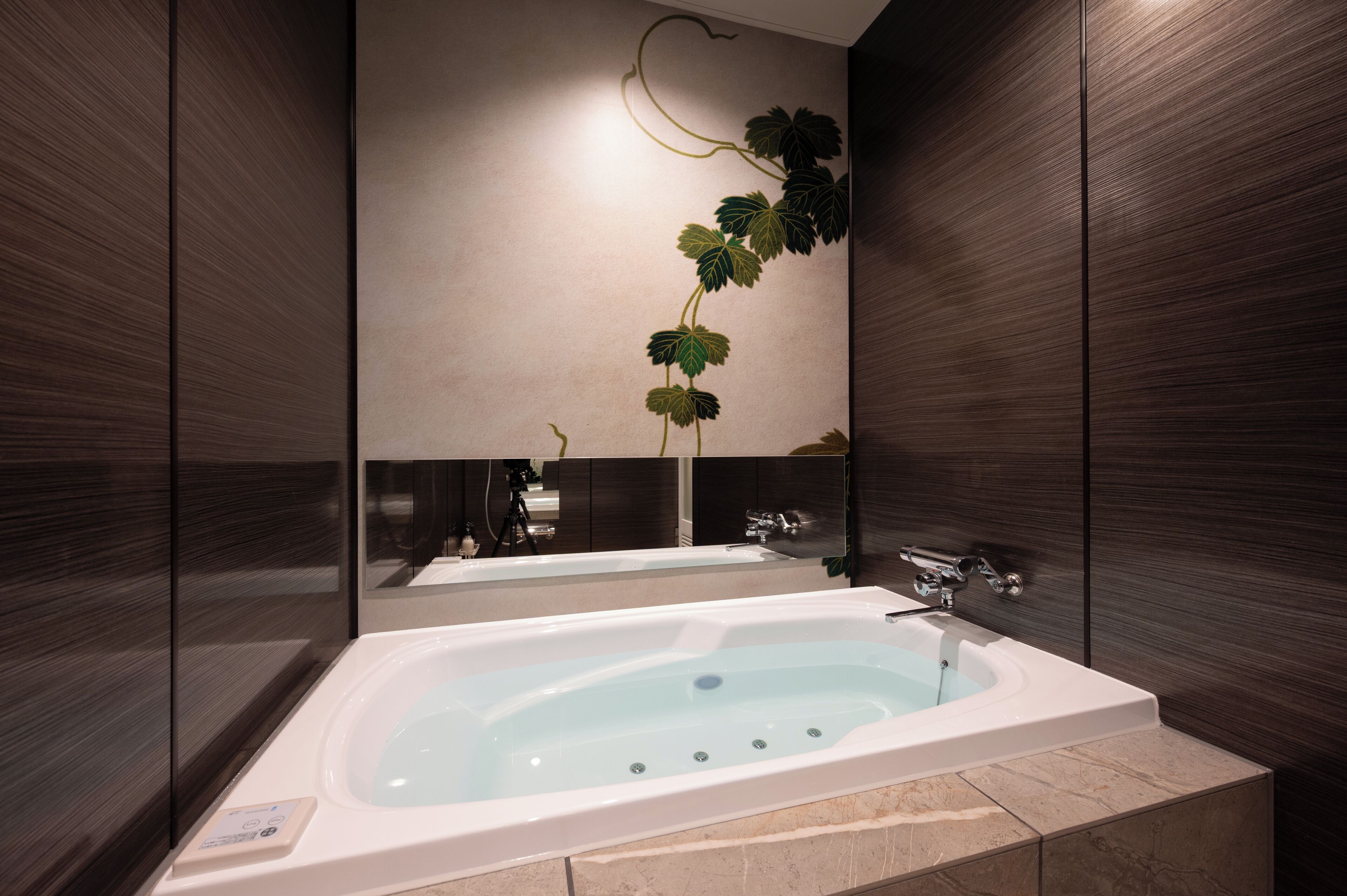 A modern bathroom with a large bathtub, dark wood paneling, and a wall-mounted mirror.